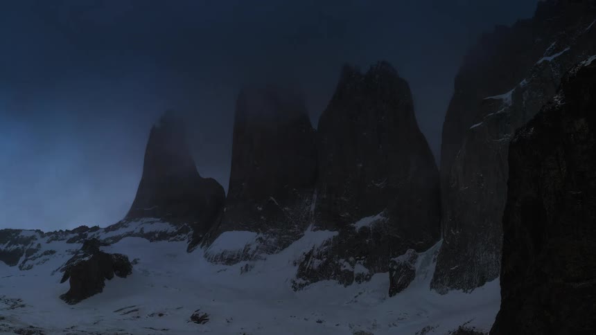 A time laps of a snow covered mountainous area shows darkness setting in as the sun sets