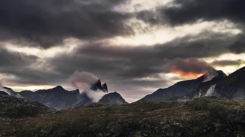 Dark clouds float over pointed mountain peaks