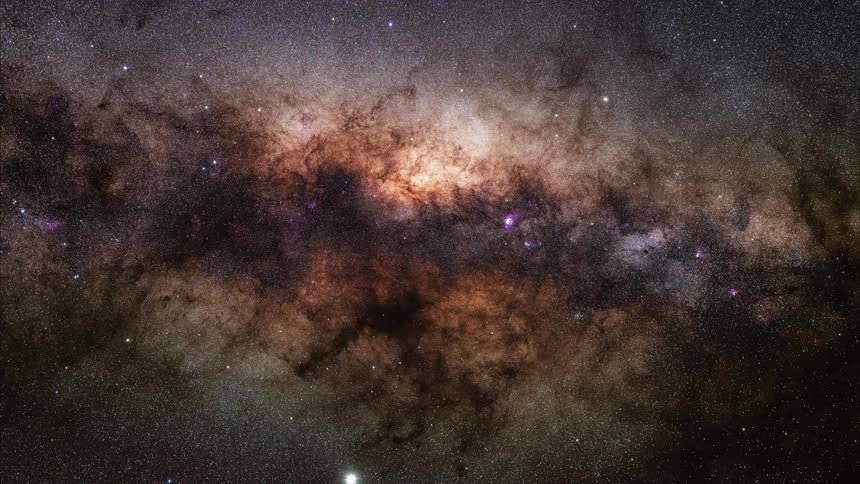 Stars twinkle in the darkness and the colors of the nebula glow in outer space