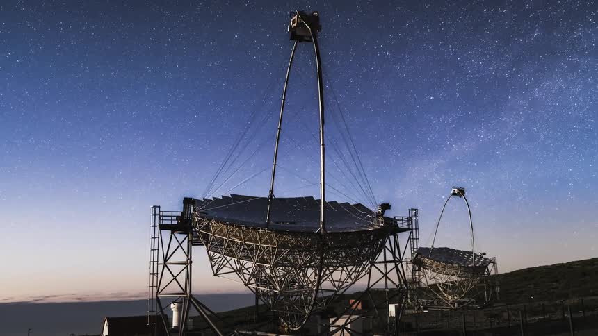 Timelapse of the silhouette of a couple telescopes following the stars on a starry night