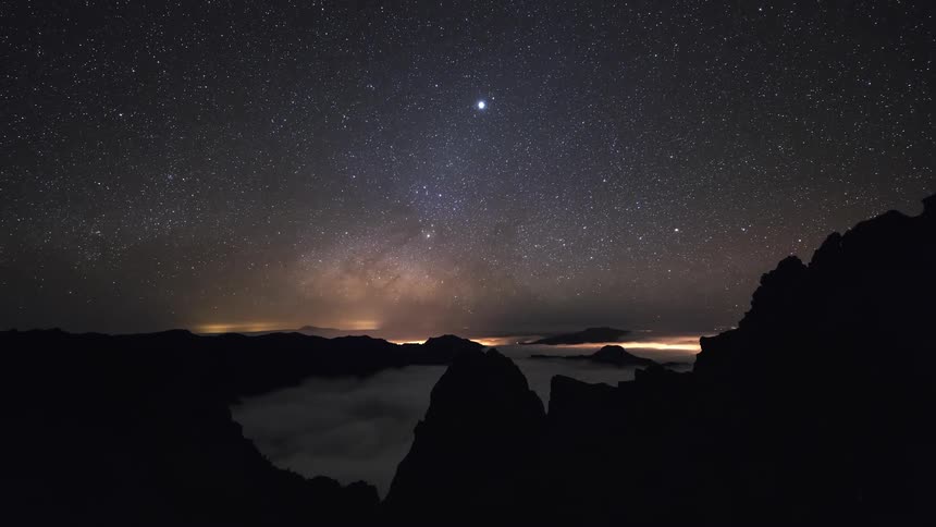 Waves ripple below glowing stars over the coast