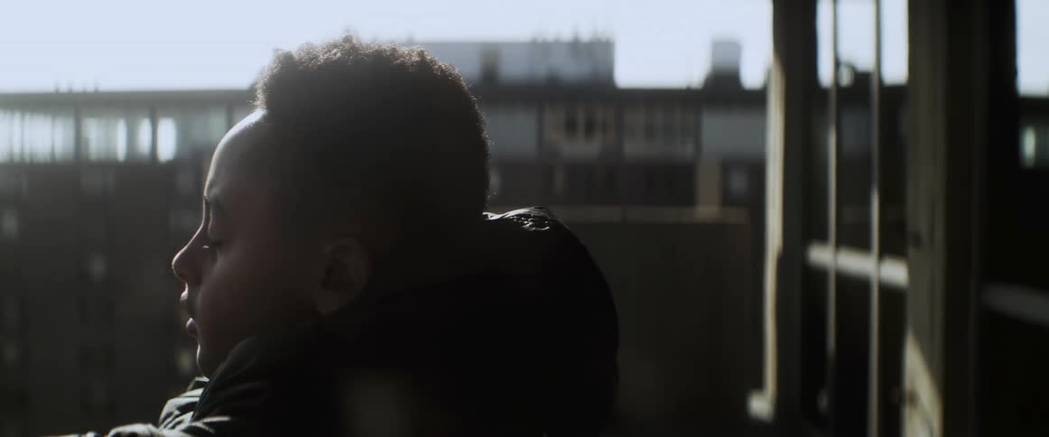A boy is standing outdoors and wearing a jacket