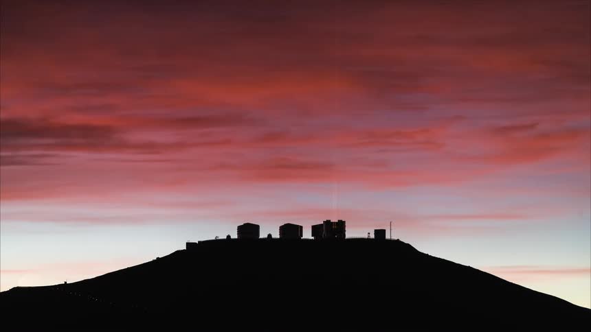 Building roof is silhouetted against the red sky
