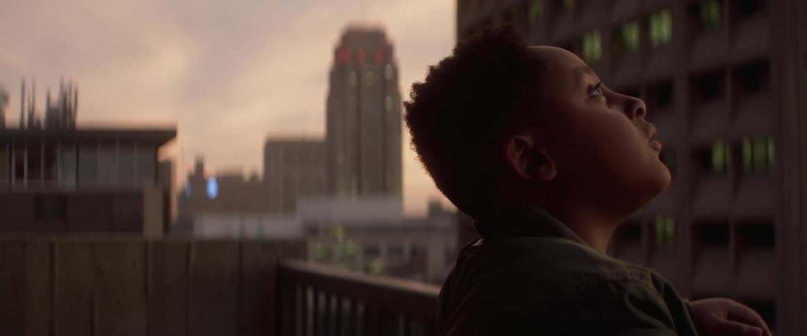 A boy is standing outdoors in a downtown city