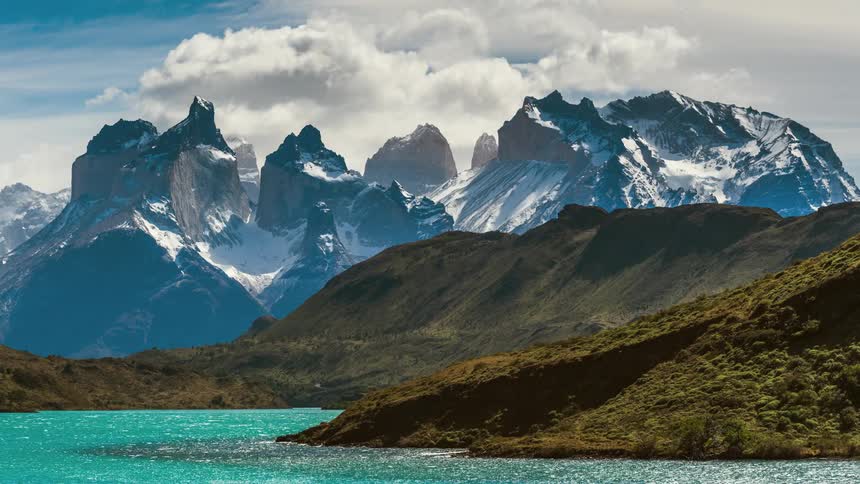 Jagged mountains are covered in snow while clouds pass overhead in this time lapse
