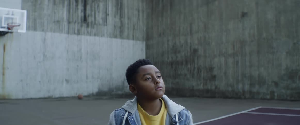 A boy looks up while sitting in a basketball court