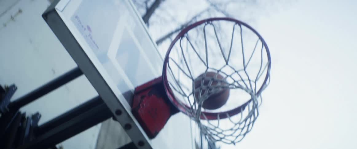 Boy with denim jacket yellow shirt and green pants plays basketball in basketball court