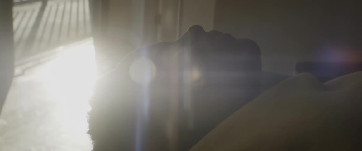 Sunlight shines in through a sliding door and projects onto a mans face as he lies on the floor