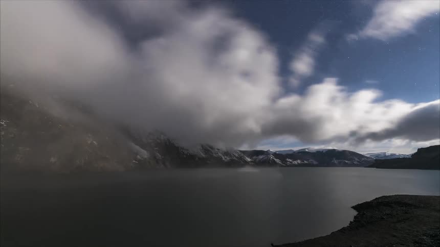 Clouds float over lake and mountains
