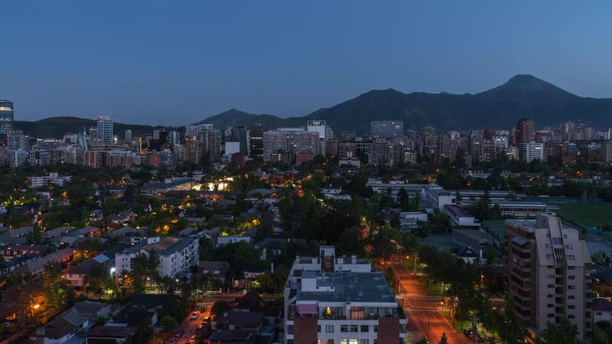 Traffic moves along street through city near mountains as night becomes day