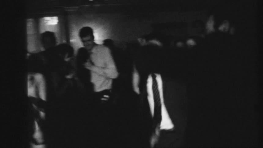 A group of friends in suits dance at a party
