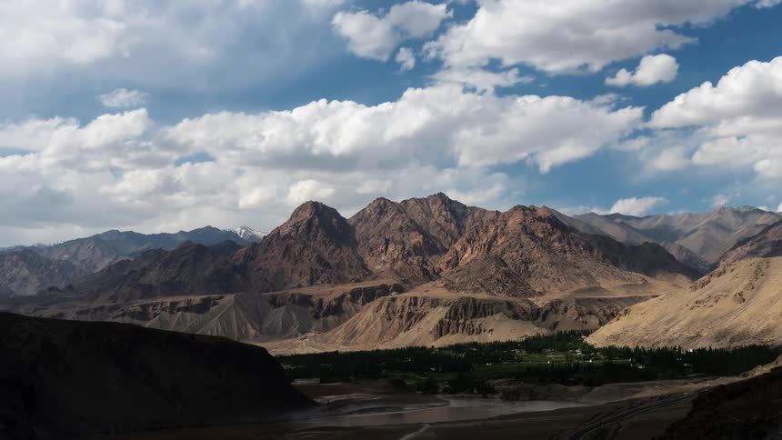 Clouds pass over an arid mountain ridge during the day
