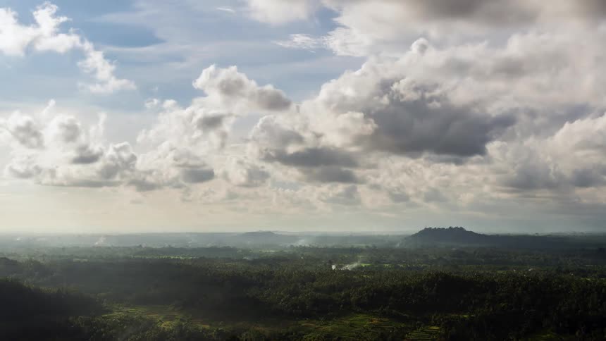 Clouds pass over a vast forested countryside during the day