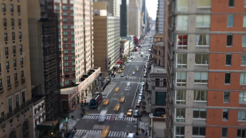 Aerial view of busy city street with traffic and people walking down in downtown area