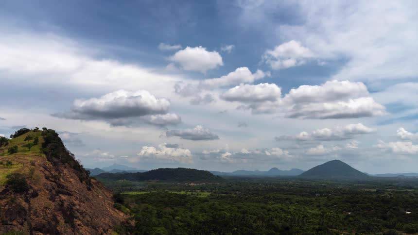 Clouds pass over a countryside covered in forest during the day