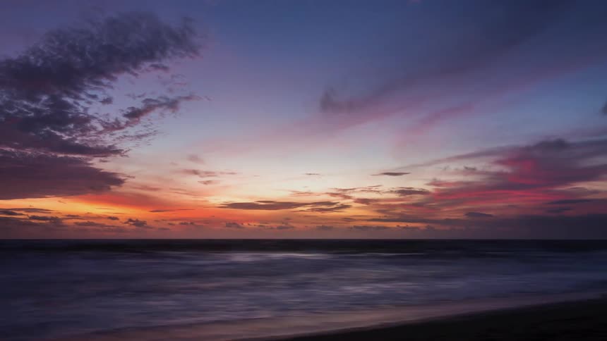 A time lapse of the ocean has a beautiful sky overhead that is filled with brilliant colors