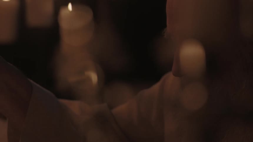 An old man in a candle-lit room reading papers
