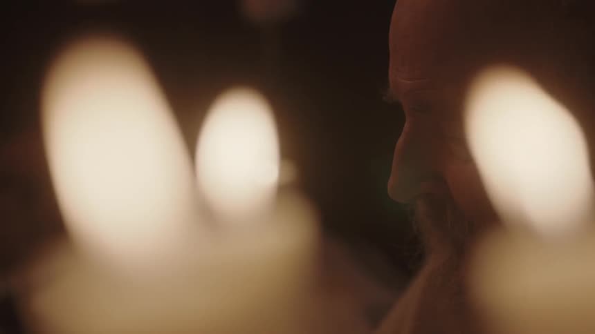 A man sits with candles all around him