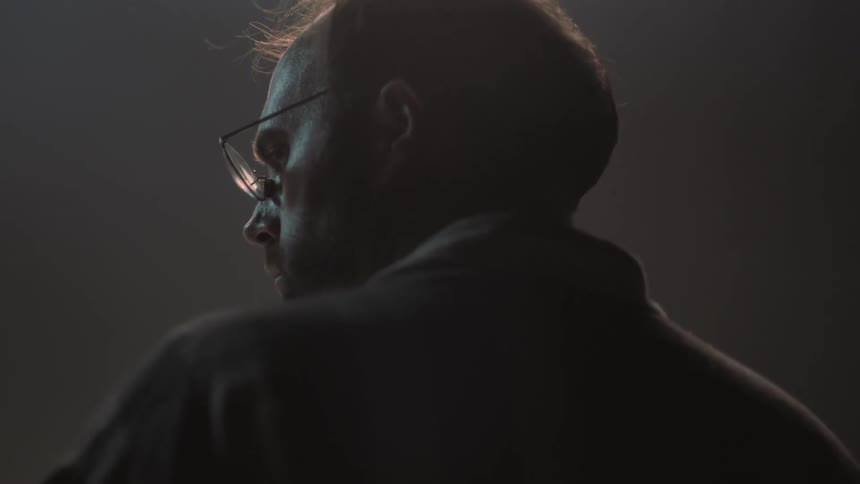 A man wearing glasses stares off to the side