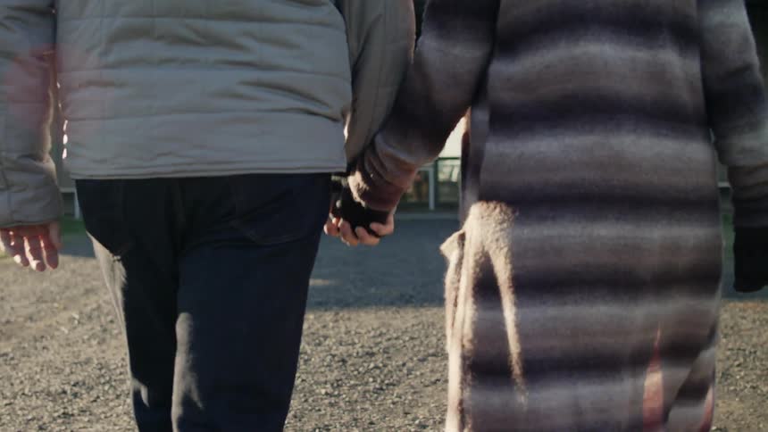 A couple is holding hands together and walking