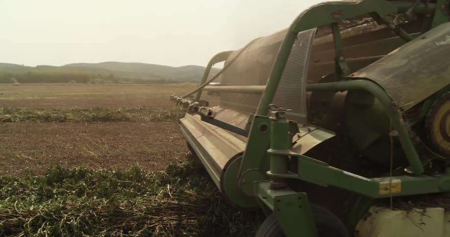 Close up of the front of a combine harvester working on a field on a farm