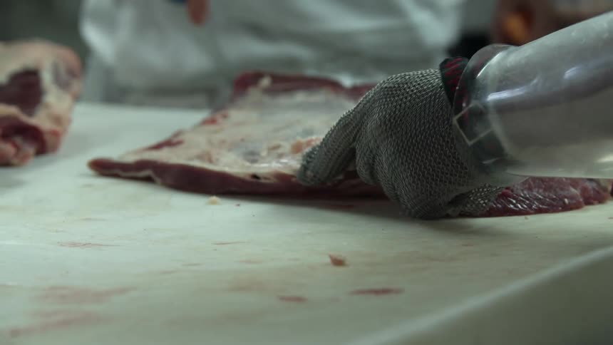 Butchers trim fat from meat