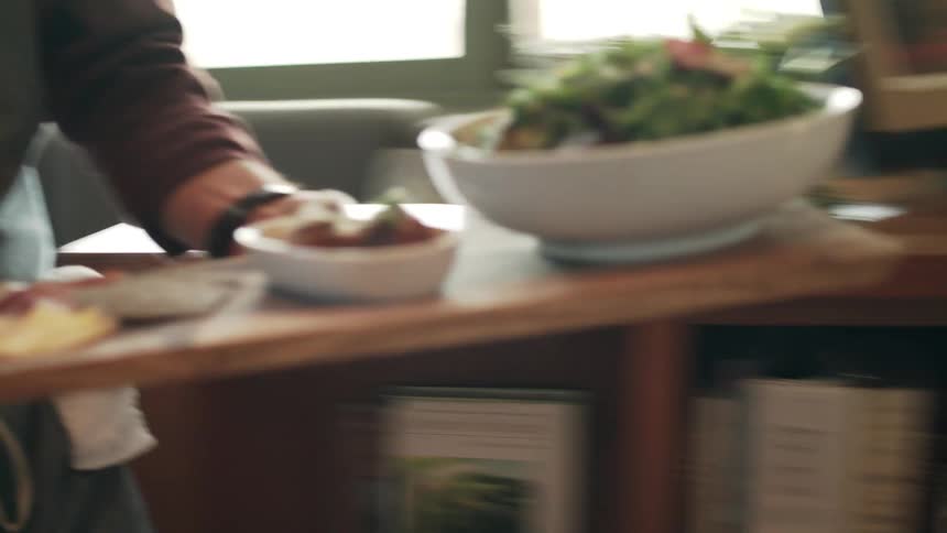 Chef brings a tray full with dishes to the dinner table at home at daytime