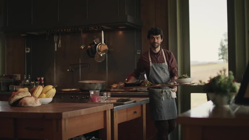 Chef brings a long tray filled with dishes from the kitchen at home