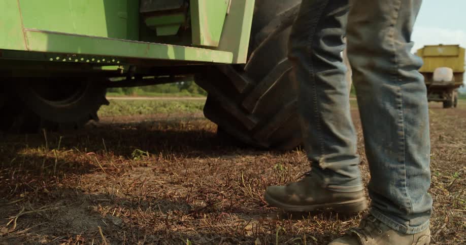 A man jumps out of a tractor on a farm
