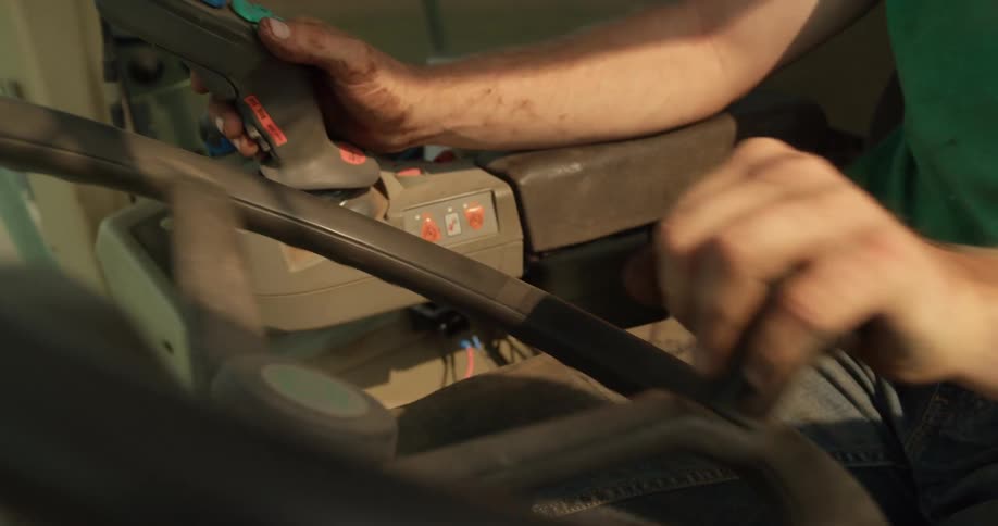 Close up of the hands of a man turning the steering wheel on a combine harvester