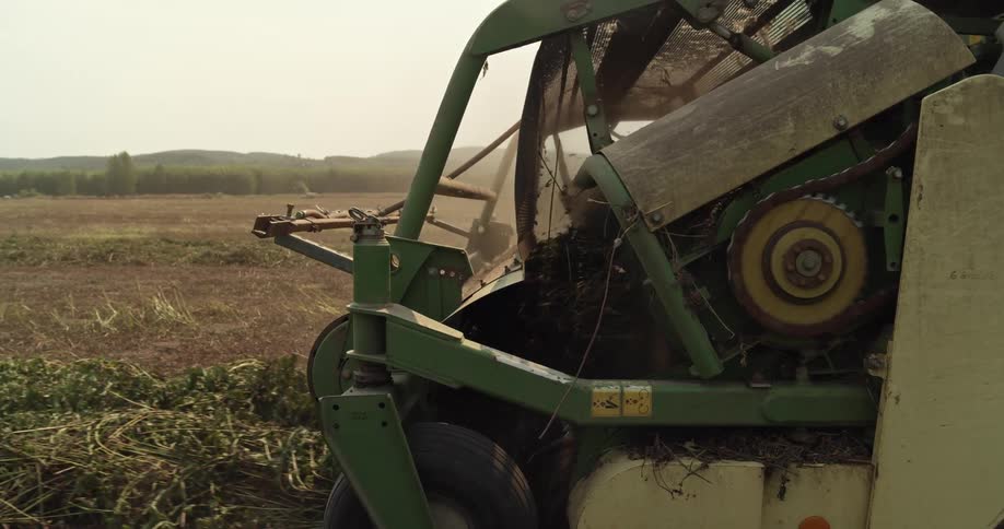 Close up of the front of a harvester moving over a field in the morning