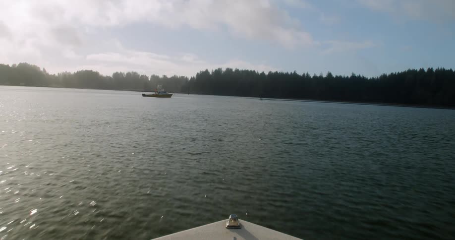 A motorboat races over the surface of a body of water while heading towards the shoreline