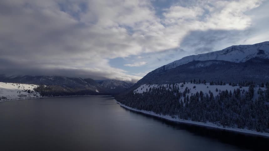 Aerial view of a lake near a snowy coast is displayed
