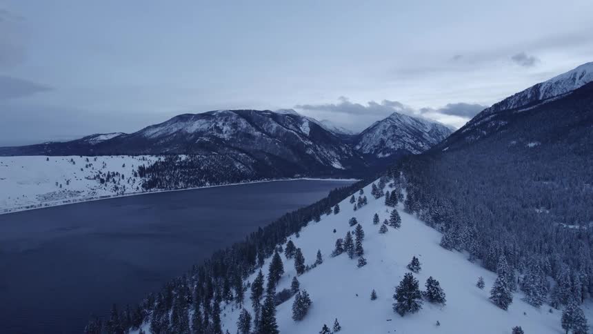 Snow covers the banks along a river and below a canyon