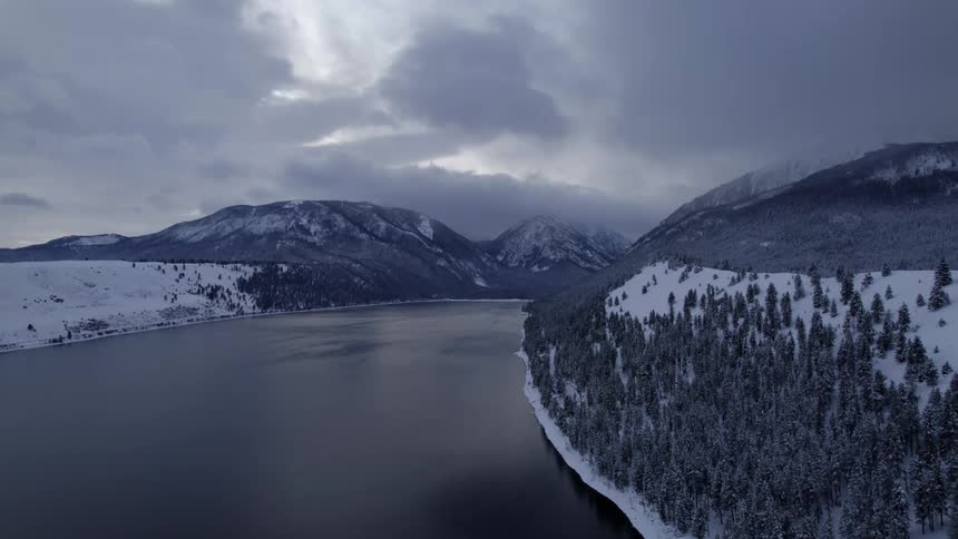 Snow covers the land surrounding a wide river and canyon