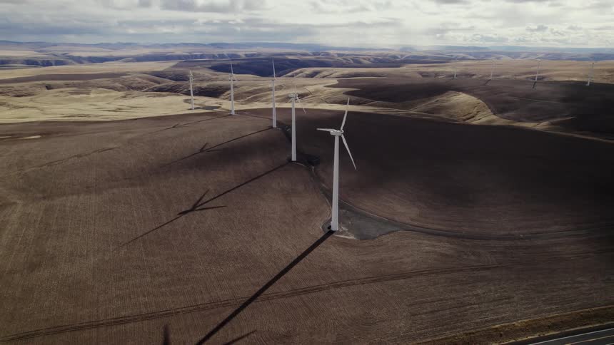 Turbines spin on a wind farm under a cloudy sky
