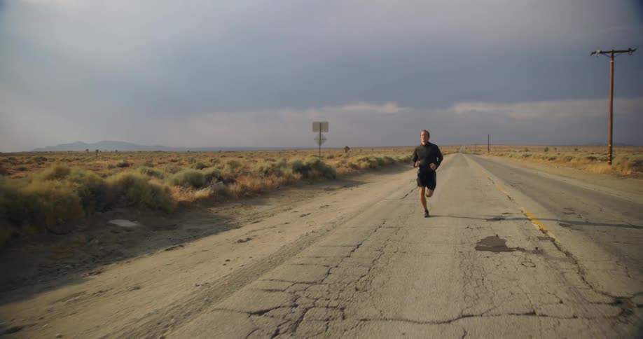 A man is jogging in a rural area during dusk