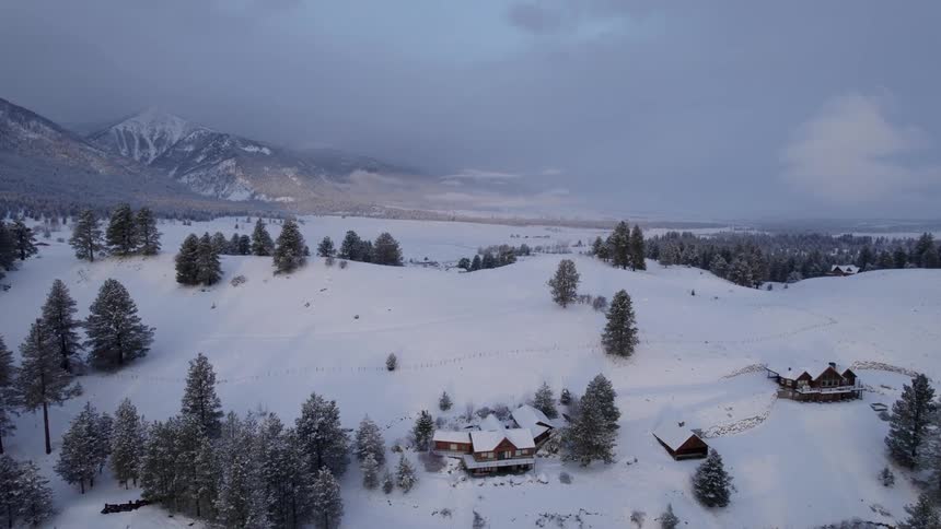 Aerial view of houses of a small town on the snow covered hills near a mountain range