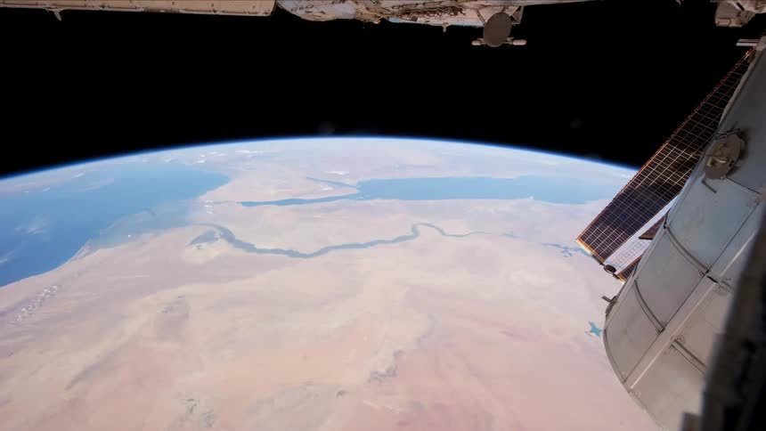 A satellite flies over the earth as it turns in the darkness of space