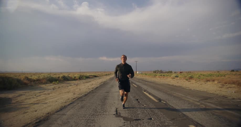 A man is seen running along a road in a deserted area
