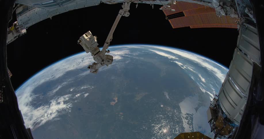 A satellite flies over the earth as it turns in the darkness of space