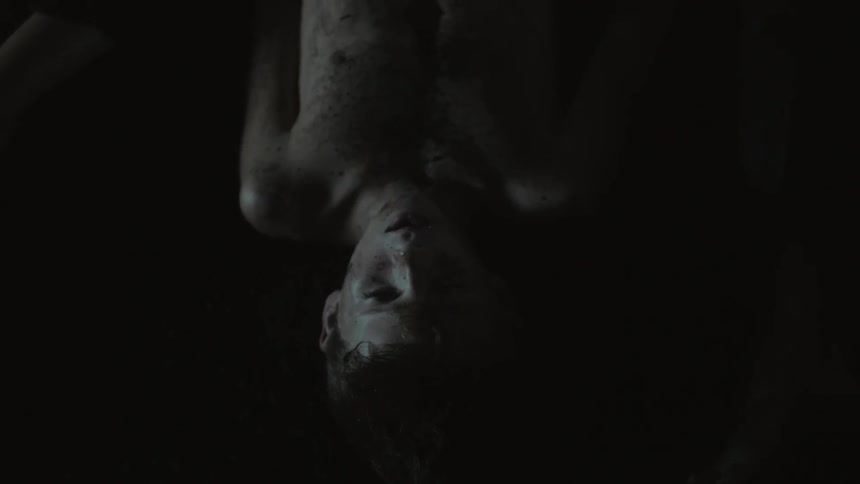 A young boy covered in dirt is hanging upside down in the dark