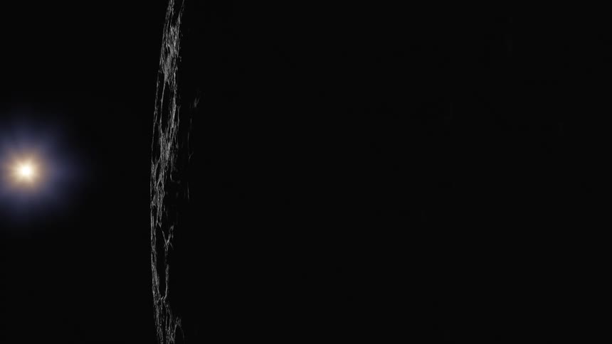 The sun moves out from behind the moon and illuminates craters on the surface