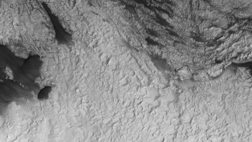 Top down aerial view of the gray surface of the rugged lunar terrain