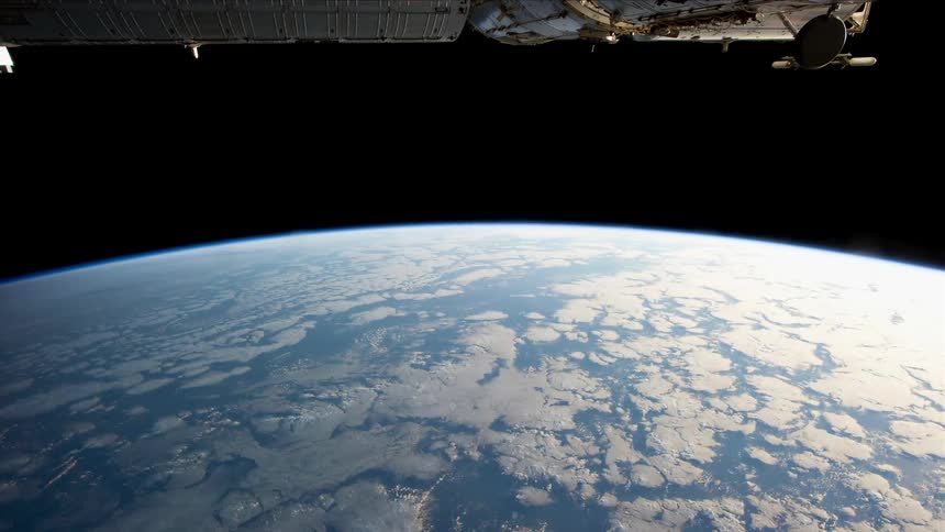 A satellite flies over the earth as it turns in the darkness of space