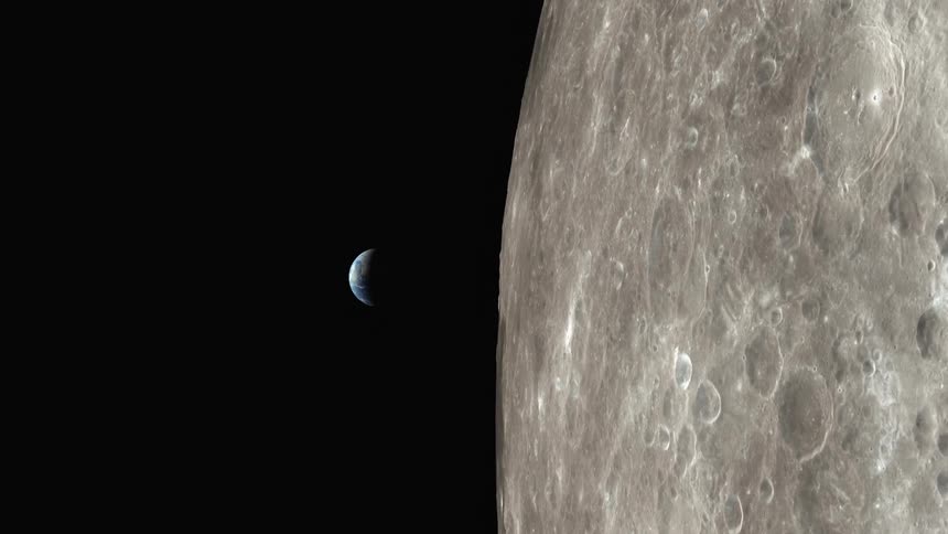 Earth rises from behind the cratered surface of the moon