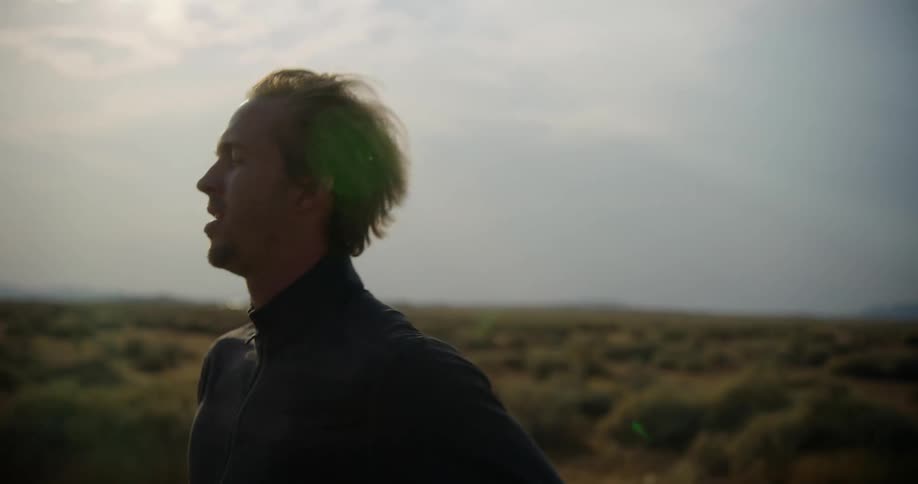 A man is running in an open rural area under a cloudy sky
