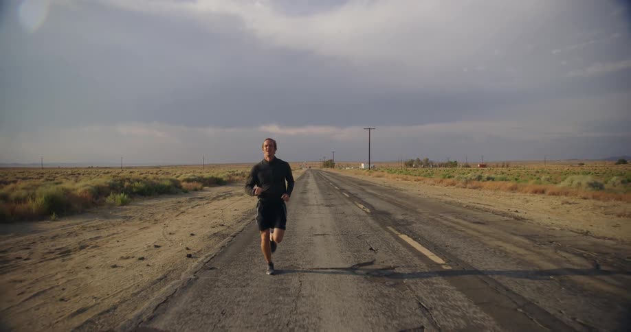 Man jogs along road through countryside under an overcast sky