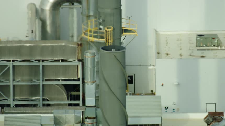 Aerial view of a manufacturing facility with emissions being released from the smoke stack
