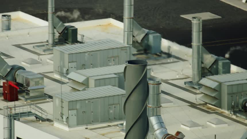 Dynamic aerial shot of a high tech carbon fiber manufacturing plant - emissions from a smokestack are visible